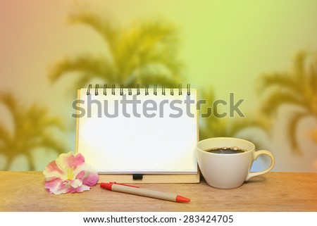 notepad and black coffee on blur palm tree and blue sky background