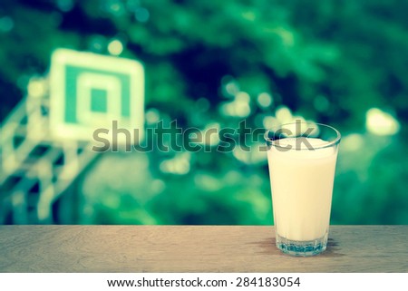 glass of cool milk on blur basketball stadium background