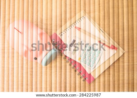 piggy bank and calculator on notepad with round wooden wall background in vintage tone