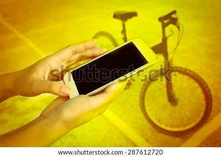 hand of child using mobile phone on blur bicycle on sport stadium background