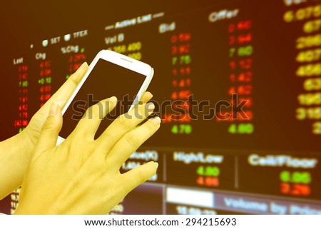 blur hand touching mobile phone on blur stock market number background
