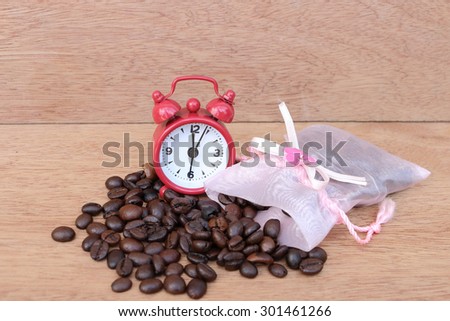 red clock on coffee seed pouring from pink bag in soft focusing