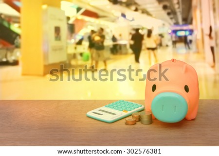 piggy bank coins and calculator on blur people in the mall background