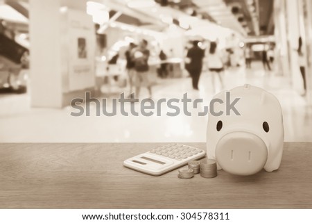 piggy bank coins and calculator on blur people in the mall background ,vintage tone