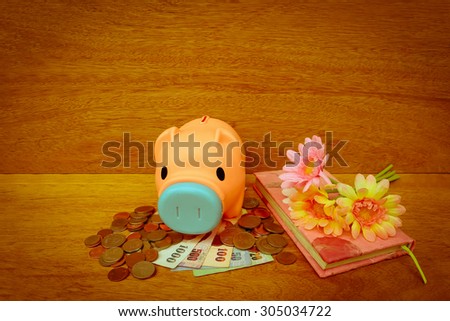 piggy bank on banknote and coins on wooden background ,vintage tone