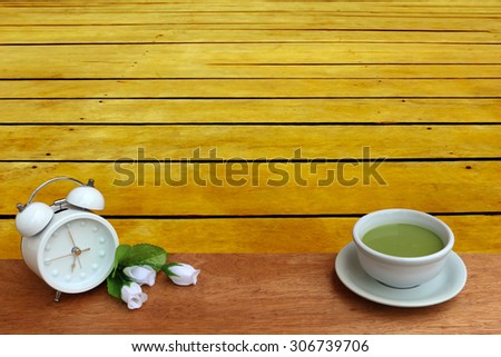 milk green tea and clock with perspective wooden floor background
