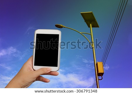 blur hand holding mobile phone  on solar cell street lamp background