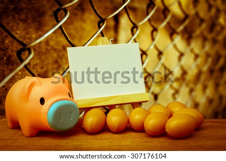piggy bank and canvas frame with blur rusty fence background  ,vintage tone