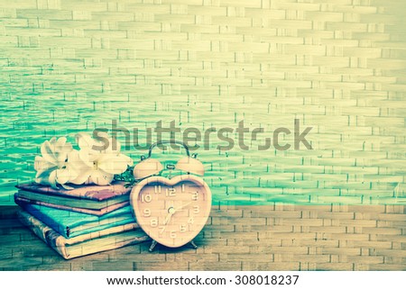 books and vintage clock on surface of woven from bamboo background  ,vintage tone