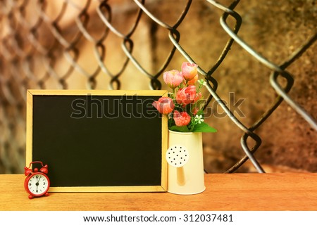 blackboard and watering pot vase with blur rusty fence background