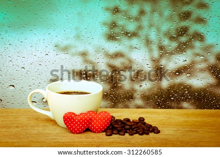 cup of coffee and coffee seed with two red heart with blur drop on mirror with dark tree background