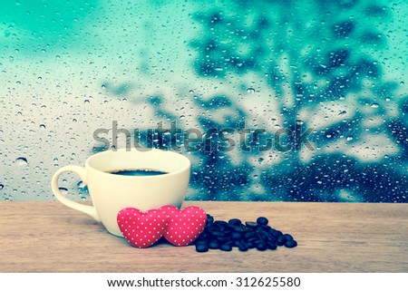 cup of coffee and coffee seed with two red heart with blur drop on mirror with dark tree background ,vintage tone