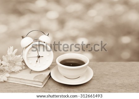 tea and flower on book with blur from yellow flower bush background ,vintage tone