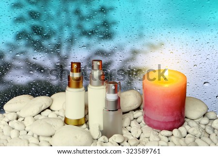 scented candles and three cosmetic containers with blur drop on mirror with dark tree background
