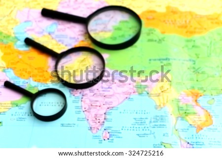 blur image of black magnifying glass on world map