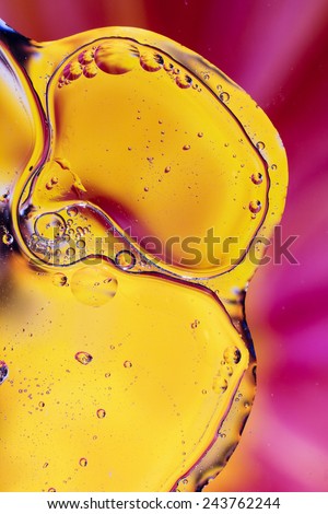 Colorful abstract shot of oil and water mixed together to show interesting bubbles patterns and shapes.  Ideal as vivid bright background, taken in portrait format. Mostly yellow and pink.