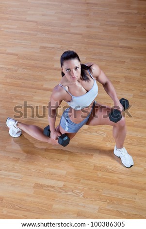 Beautiful athletic trainer shows examples of exercises in the gym