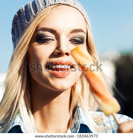 Smiling blond girl with plump sexy lips and smokey eye make up looks at sweet delicious fruit ice cream