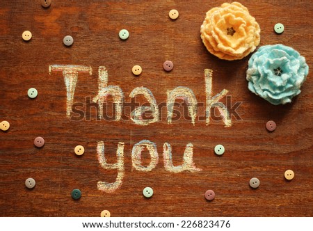 thank you note, buttons and wool flowers on wood background