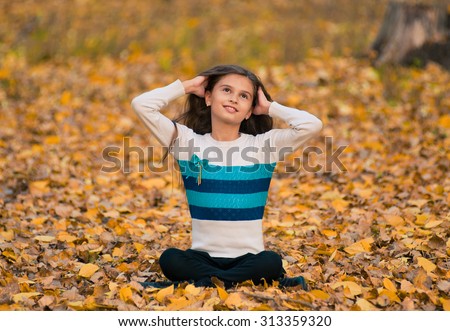 Girl sitting in autumn with falling leaves wondering about something