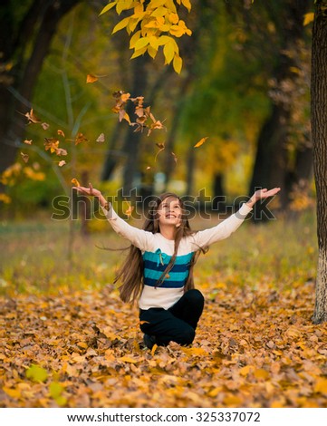 Excited cheerful girl drop up leaves,  joyful with beautiful autumn colors