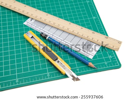 A wood ruler, cutter, cutting mat, pencil isolated over a white background