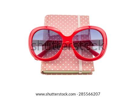 Red sunglasses and Pink color cover fabric note book isolated on white background