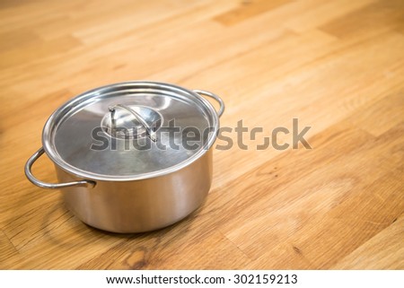 Small cute stainless steel pot on wooden in warm light - selective focus