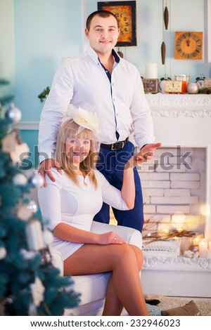 Happy young people are sitting Christmas tree, near the fireplace  and hold hands