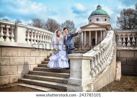 Beautiful bride and groom hugging on stairs in front of old building with columns