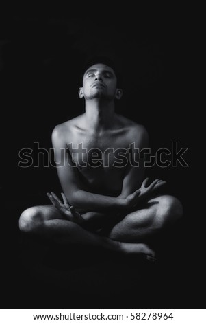 Meditation young naked man on a black background