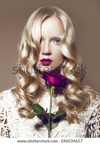 Beautiful Blonde Young Model With Bright Makeup And Manicure And With a Rose,Curly Hair,White Dress