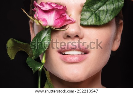 Close-up shot of sexy woman  lips with pink lipstick and beautiful pink rose, beautiful smile