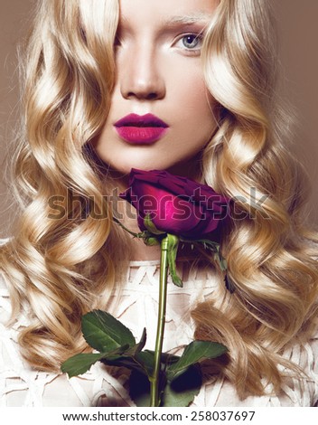 Beautiful Blonde Young Model With Bright Makeup And Manicure And With a Rose,Curly Hair,White Dress