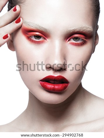 Close-up shot of a girl\'s eye with makeup and fingers with colorful manicure,red lips,red shadows