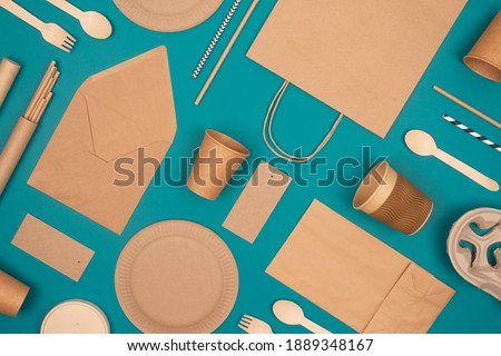 Flat lay with eco-friendly tableware - kraft paper food packaging on green background. Street food paper packaging, recyclable paperware, zero waste packaging concept. Mockup, selective focus