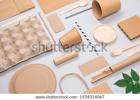 Set of eco-friendly tableware and kraft paper food packaging on light gray background. Street food paper packaging - cups, plates, straws, containers and paper bags. Mockup, flat lay