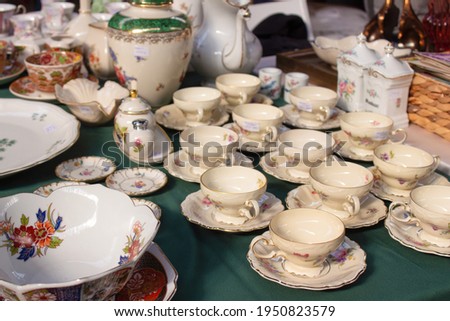 Antiques on flea market or festival - vintage porcelain tea cups, tableware and other vintage things. Collectibles memorabilia and garage sale concept. Selective focus