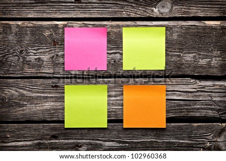 Blank different colors sticky note paper sheets. Closeup on old vintage wooden table.