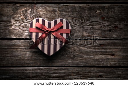 Heart shaped Valentines Day gift box on old wood. Vintage holiday background.