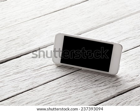 White smart phone with isolated screen on white wooden desk.