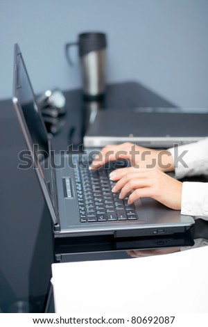 Closeup of woman\'s hands touching notebook (laptop) keys during work. In office interior.