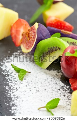 Closeup of sliced fresh fruits on black stone.