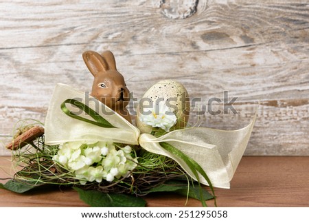 Easter bunny with easter egg in the nest against wooden background as an Easter greeting with free text space