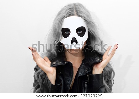 Young woman in skull mask; face of a young woman in paper halloween mask