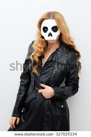 Young woman in skull mask; face of a young woman in paper halloween mask