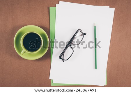 Vintage color. Mobile with blank paper or notebook and cup of coffee. Simple workspace or coffee break with relaxing composing. Blank paper and colorful pencils on the wooden table. View from above
