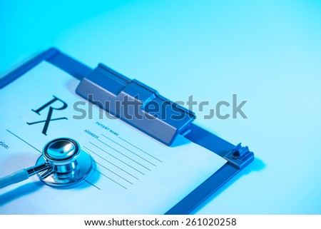 Empty medical prescription and Stethoscope on blue, reflective background