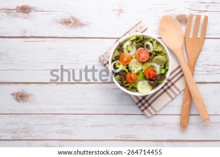 Bowl of Summer Salad. Fresh healthy salad on wooden table. View from above with copy space. bowl of leafy green salad with olives, tomatoes and cucumber.