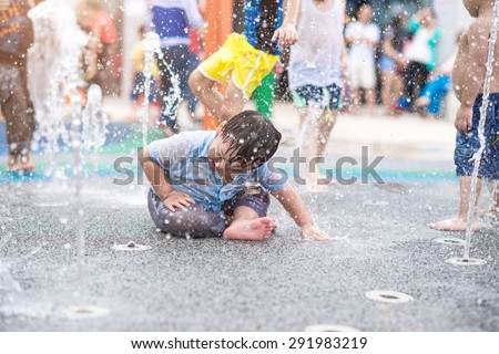 A boy playing with water in park fountain. Hot summer. Happy young boy has fun playing in water fountains